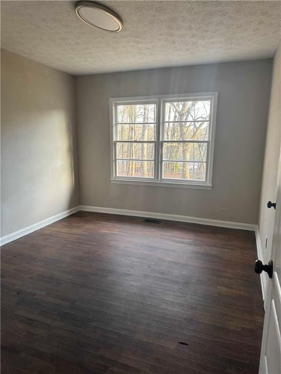 empty room featuring dark hardwood / wood-style floors and a textured ceiling