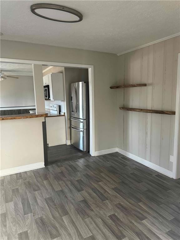 kitchen with wooden counters, dark hardwood / wood-style flooring, ceiling fan, stainless steel appliances, and a textured ceiling