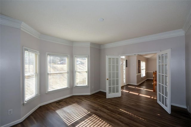 empty room featuring french doors, dark hardwood / wood-style flooring, crown molding, and a wealth of natural light