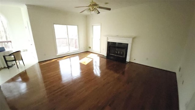 unfurnished living room with ceiling fan, dark wood-style flooring, and a fireplace with flush hearth