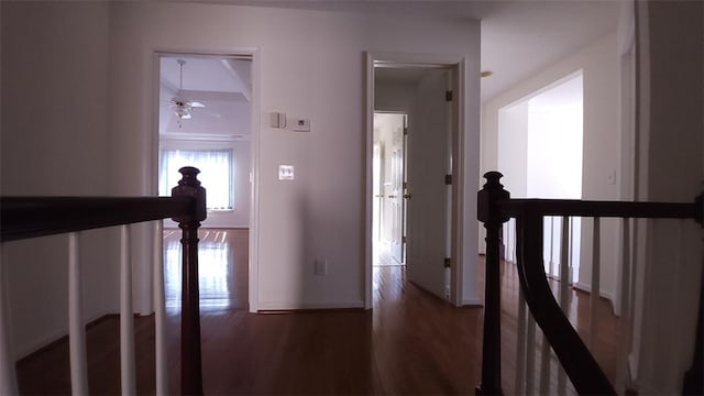 corridor with dark wood finished floors and an upstairs landing