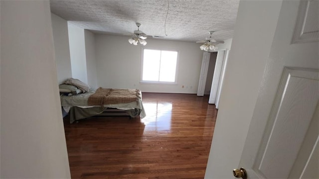 bedroom with a ceiling fan, dark wood finished floors, and a textured ceiling