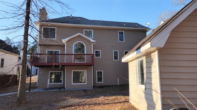 rear view of property featuring a chimney and a wooden deck