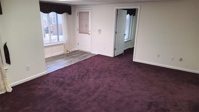 interior space with a paneled ceiling, baseboards, and dark colored carpet