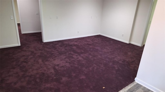 empty room featuring dark carpet and baseboards