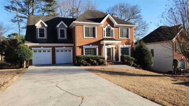 colonial house with driveway, a garage, and brick siding