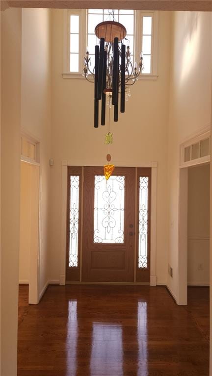 foyer with dark wood-type flooring, plenty of natural light, and a notable chandelier