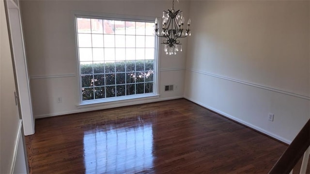 unfurnished room with dark wood-style floors, baseboards, visible vents, and a chandelier