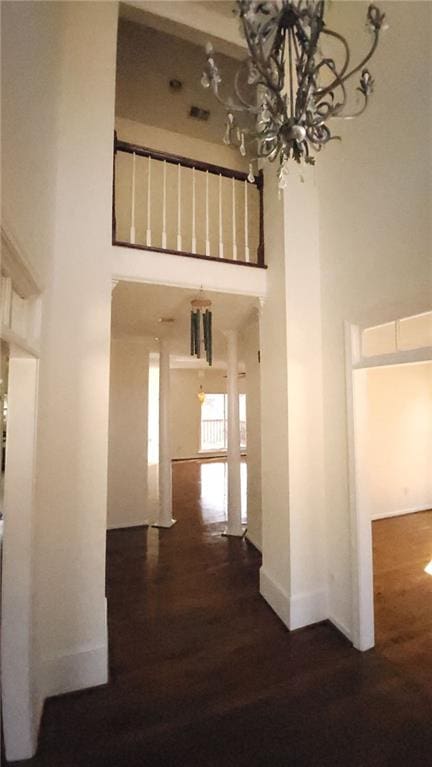 hall with dark wood-style floors, a towering ceiling, and baseboards