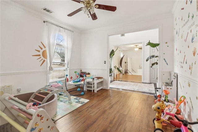 rec room with hardwood / wood-style flooring, ceiling fan, and crown molding