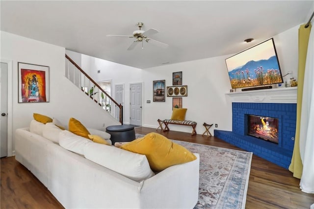 living room with a brick fireplace, dark hardwood / wood-style flooring, and ceiling fan