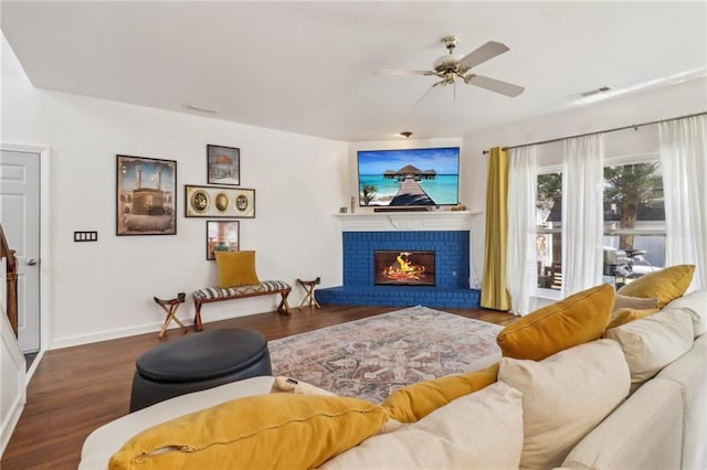 living room featuring ceiling fan, a brick fireplace, and dark wood-type flooring