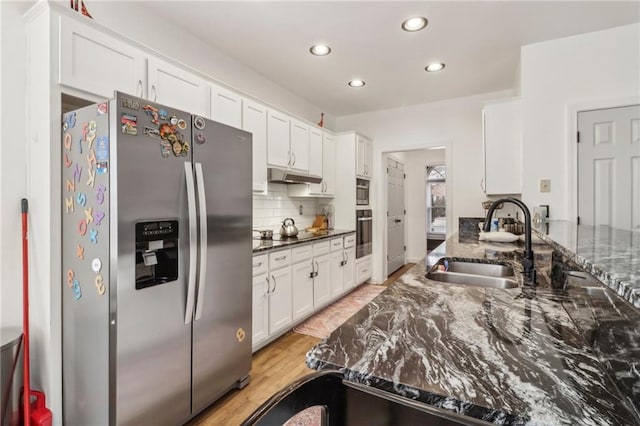 kitchen featuring stainless steel refrigerator with ice dispenser, sink, white cabinets, wall oven, and dark stone countertops