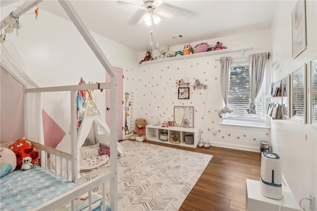 bedroom with hardwood / wood-style flooring, ceiling fan, and a crib