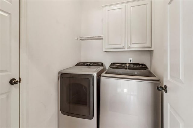 clothes washing area featuring cabinets and separate washer and dryer