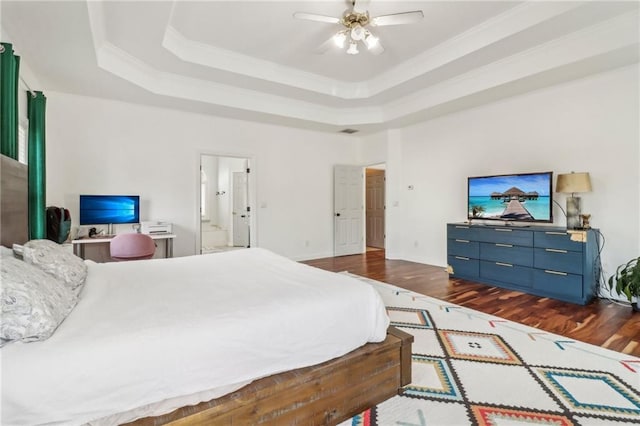 bedroom featuring ceiling fan, dark wood-type flooring, a tray ceiling, and ensuite bathroom