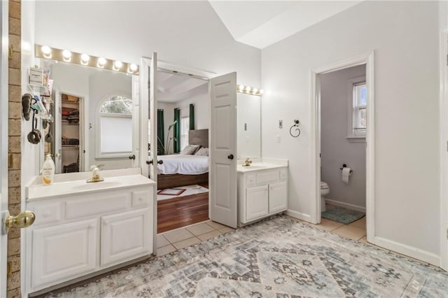 bathroom with toilet, a healthy amount of sunlight, lofted ceiling, and tile patterned flooring