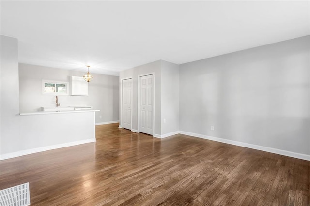 empty room with a notable chandelier and dark hardwood / wood-style flooring