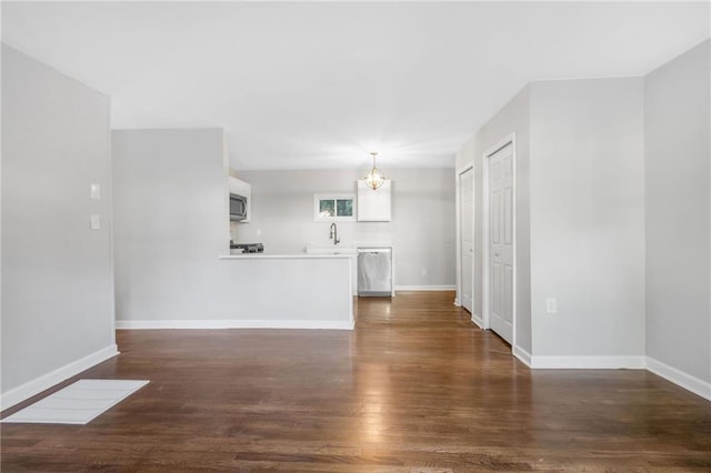 unfurnished living room with a notable chandelier, dark hardwood / wood-style flooring, and sink