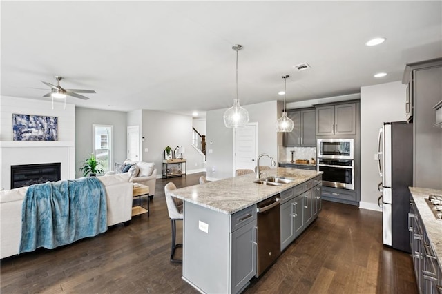 kitchen featuring open floor plan, gray cabinetry, stainless steel appliances, and a sink