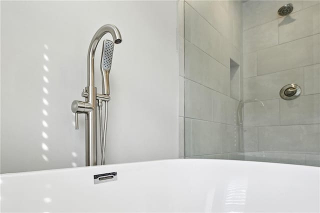 room details featuring a tile shower and a sink