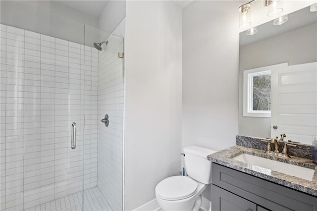 bathroom with vanity, toilet, baseboards, and a stall shower