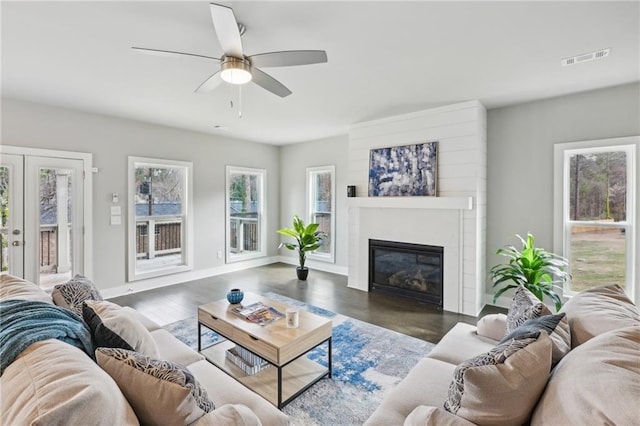 living area featuring visible vents, baseboards, french doors, wood finished floors, and a glass covered fireplace