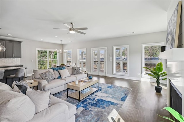 living room featuring recessed lighting, ceiling fan with notable chandelier, baseboards, and dark wood-style flooring