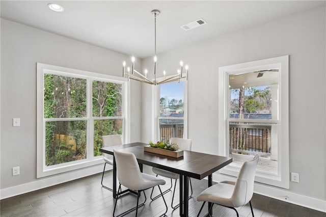 dining area with a wealth of natural light, visible vents, a chandelier, and dark wood finished floors