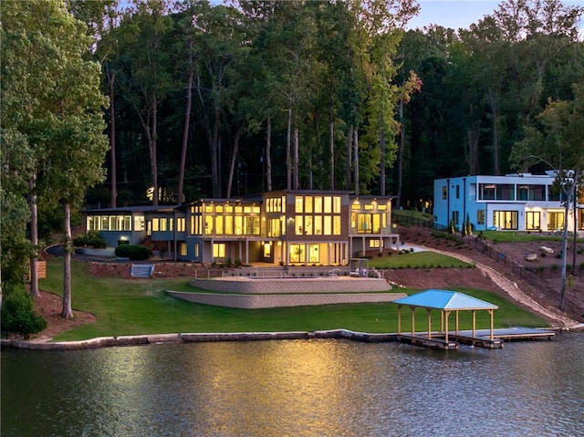 rear view of property featuring a water view and a lawn