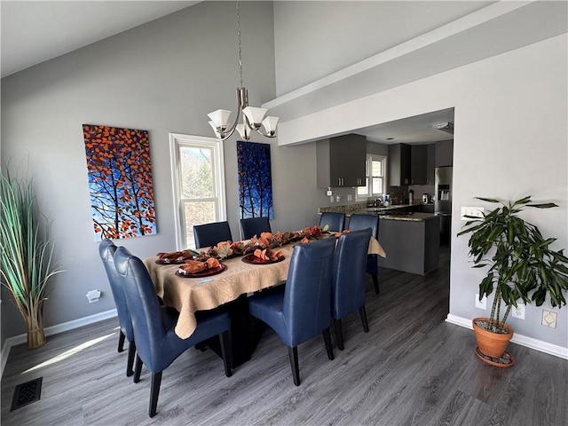 dining space with a healthy amount of sunlight, an inviting chandelier, visible vents, and wood finished floors