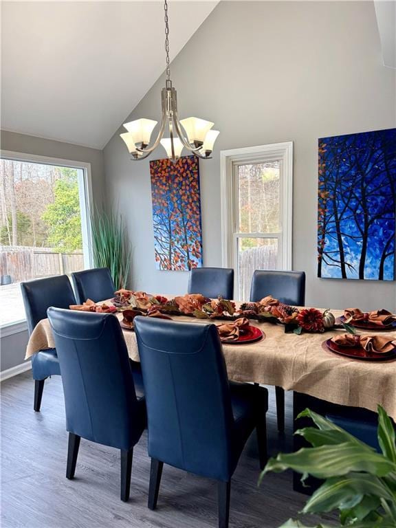 dining area featuring a chandelier, high vaulted ceiling, and wood finished floors