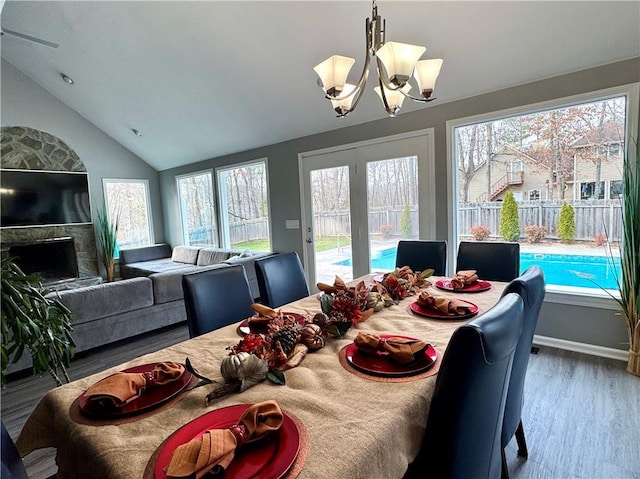 dining room featuring lofted ceiling, baseboards, a chandelier, and wood finished floors