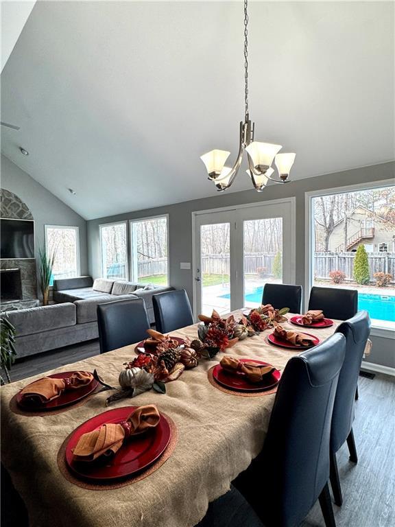 dining space with a chandelier, lofted ceiling, and wood finished floors