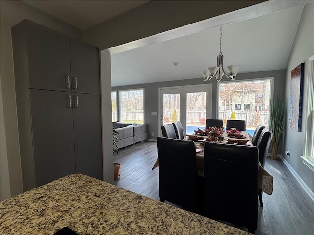 dining room with dark wood-style floors, baseboards, a chandelier, and vaulted ceiling