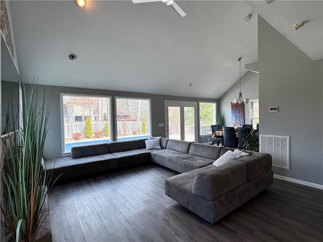 living area featuring high vaulted ceiling, dark wood-type flooring, visible vents, baseboards, and an inviting chandelier