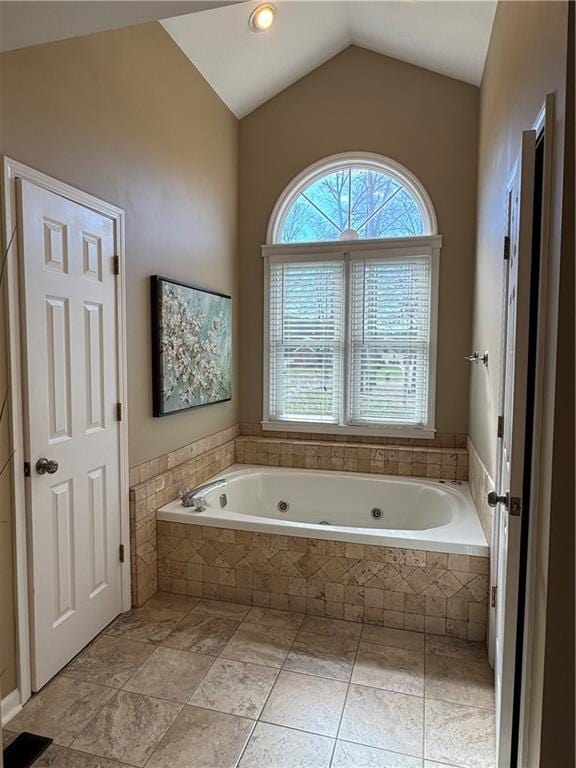 full bathroom with lofted ceiling, a jetted tub, and a healthy amount of sunlight