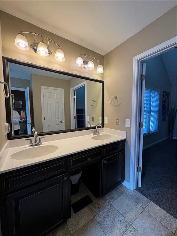 bathroom featuring ensuite bathroom, double vanity, and a sink