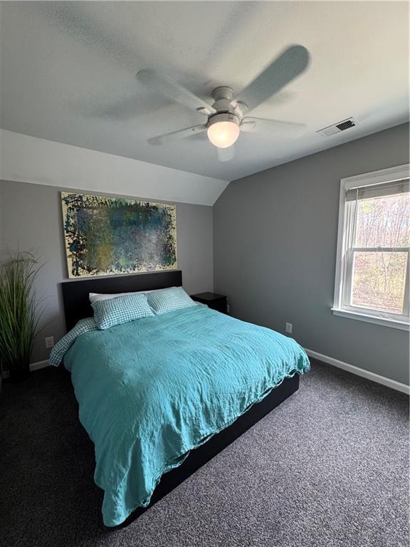 carpeted bedroom with vaulted ceiling, ceiling fan, visible vents, and baseboards