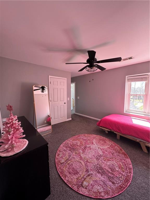 carpeted bedroom featuring a ceiling fan, visible vents, and baseboards