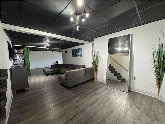 living room featuring a paneled ceiling, stairs, baseboards, and wood finished floors