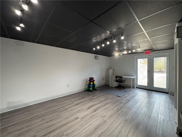 interior space with wood finished floors, a paneled ceiling, and baseboards