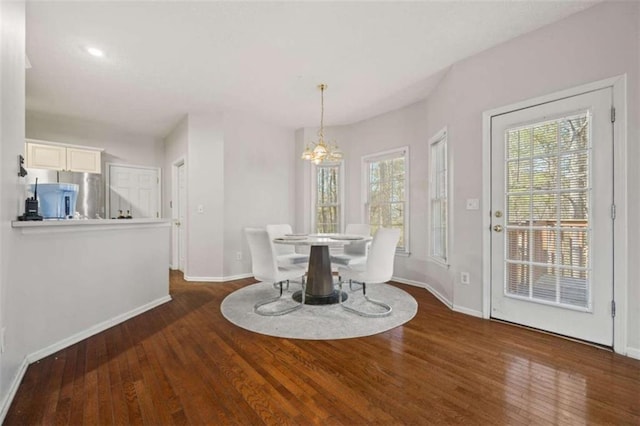 dining area featuring wood-type flooring, a chandelier, and baseboards