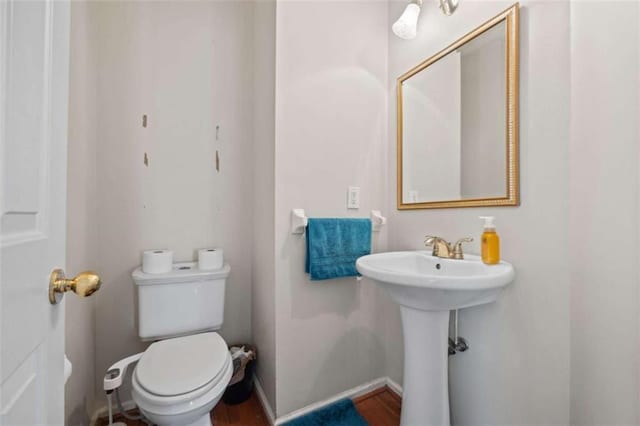 half bathroom with a sink, toilet, and baseboards