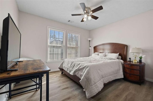 bedroom with wood finished floors, visible vents, and baseboards