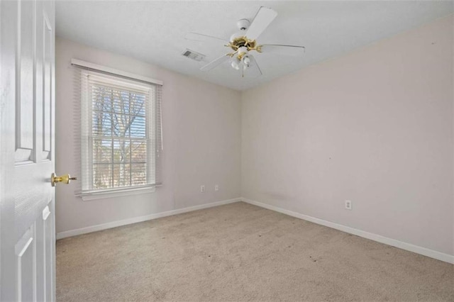 carpeted spare room featuring ceiling fan, visible vents, and baseboards