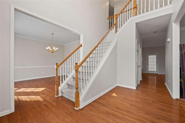 stairs featuring a chandelier, baseboards, and wood finished floors