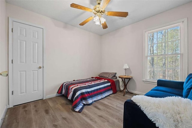 bedroom with wood finished floors, a ceiling fan, and baseboards