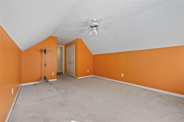 bonus room featuring baseboards, lofted ceiling, ceiling fan, carpet, and a textured ceiling