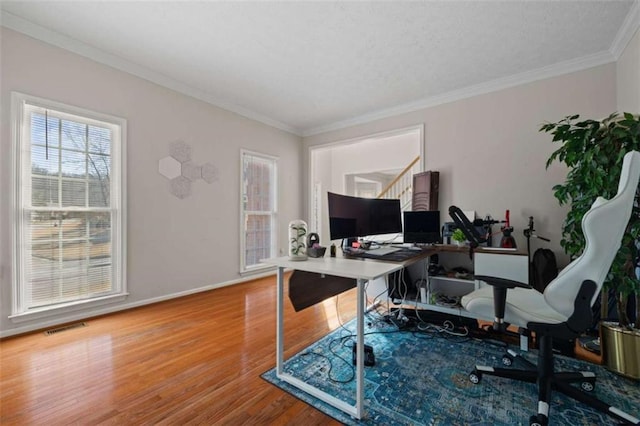 office featuring visible vents, crown molding, baseboards, and wood finished floors